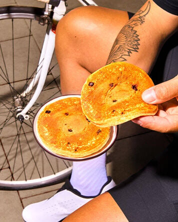 Pancakes prot&eacute;in&eacute;s tenues &agrave; la main pr&egrave;s d&rsquo;un v&eacute;lo lors d&rsquo;une pause sportive."