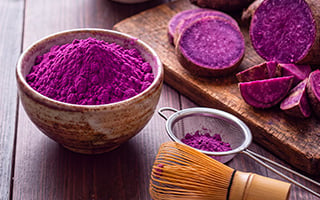 visuel d'une poudre violette &agrave; l'ub&eacute; dans un bol, et morceaux d'igname violette pos&eacute;e sur une planche de bois
