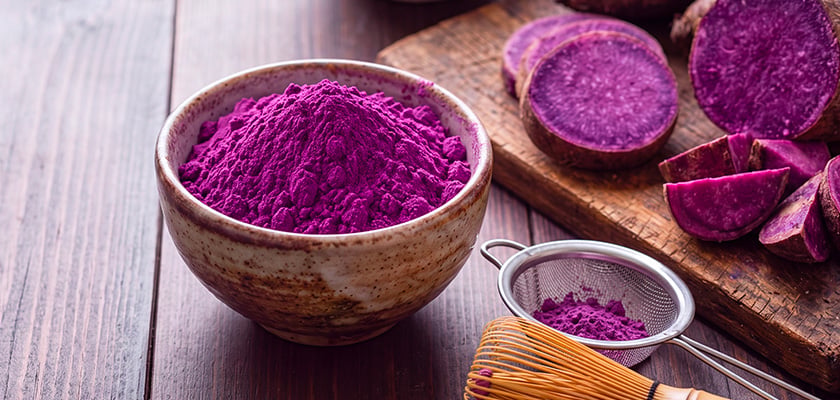 visuel d'une poudre violette &agrave; l'ub&eacute; dans un bol, et morceaux d'igname violette pos&eacute;e sur une planche de bois